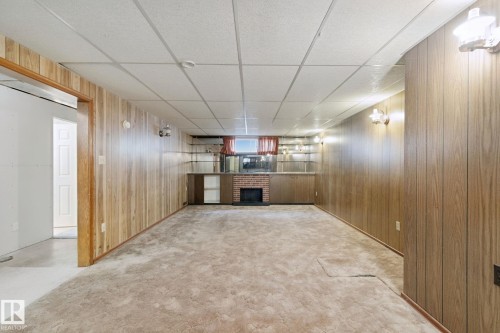 Spacious interior featuring wood-panel walls, drop ceiling, and wall-mounted sconces - 8424 70 Street Nw, Edmonton, AB 