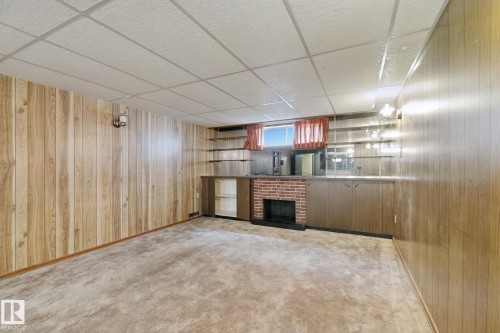 Recessed drop ceiling, wood-finish paneling, built-in fireplace, built-in cabinetry, and integrated shelving - 8424 70 Street Nw, Edmonton, AB 