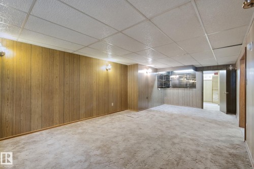 Spacious interior with neutral carpeting and wood-panel accent walls - 8424 70 Street Nw, Edmonton, AB 