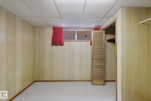 Wood-finish wall paneling, drop ceiling, carpeted flooring, and a louvered bi-fold door - 8424 70 Street Nw, Edmonton, AB 
