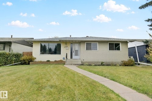 Single-story residence with a concrete walkway, established front lawn, and mature landscaping - 8424 70 Street Nw, Edmonton, AB 