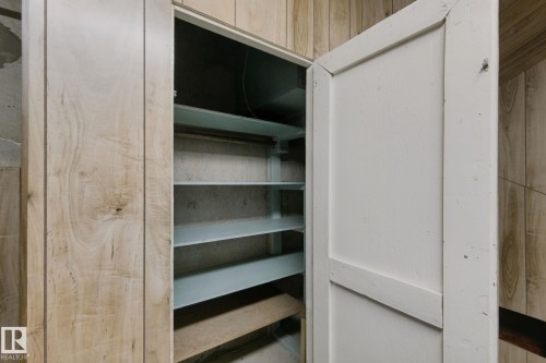 Built-in storage cabinet with multiple shelves, featuring a white painted door and wood-paneling surround - 8424 70 Street Nw, Edmonton, AB 