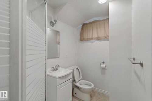 Shower with frosted glass enclosure, single vanity with integrated sink, wall-mounted mirror, and tile flooring - 8424 70 Street Nw, Edmonton, AB 