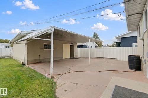 Paved patio with an attached carport, stucco exterior, and a solid fence - 8424 70 Street Nw, Edmonton, AB 