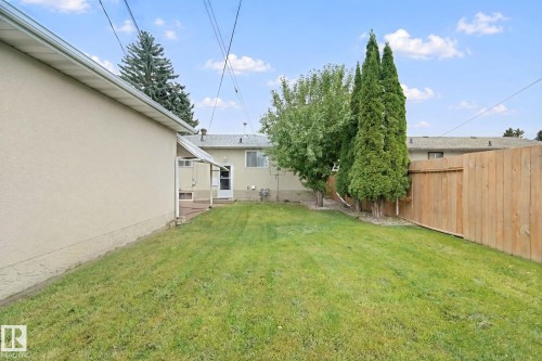 Expansive backyard featuring a manicured lawn, mature trees, and a privacy fence - 8424 70 Street Nw, Edmonton, AB 