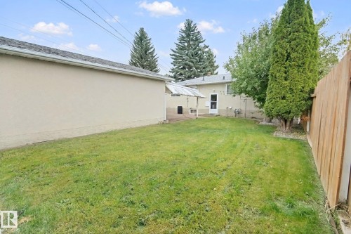 Expansive lawn area with a wood fence, mature trees, and a covered patio structure - 8424 70 Street Nw, Edmonton, AB 