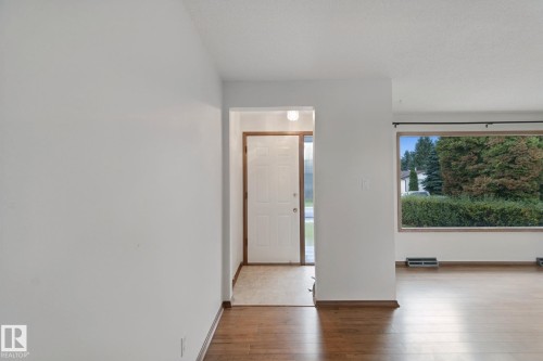 Wood-finish flooring throughout, white walls, and a large window with dark trim - 8424 70 Street Nw, Edmonton, AB 