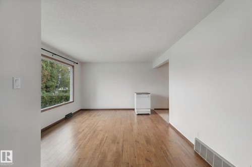 Hardwood-finish flooring, crisp white walls, and a large window with wood trim - 8424 70 Street Nw, Edmonton, AB 
