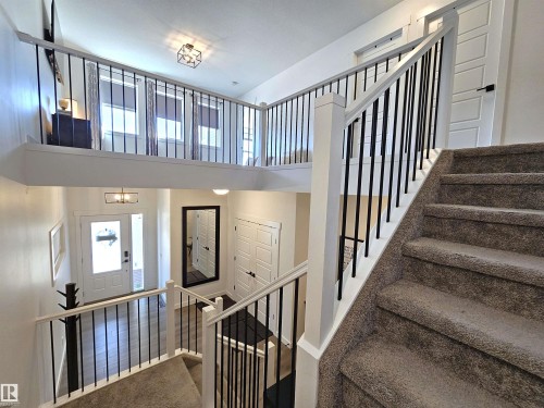 Multi-level interior featuring a carpeted staircase, white railing with black balusters, and a lofted area - 40 Jamison Crescent, St. Albert, AB 