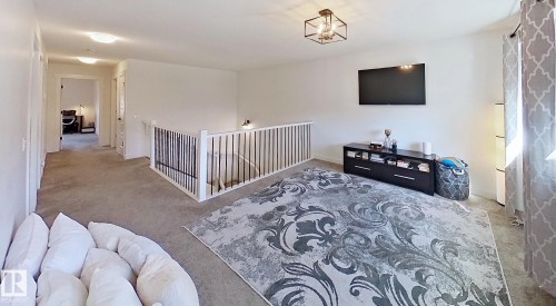 Carpeted open-concept bonus room featuring a metal and wood railing, recessed lighting, and a contemporary ceiling fixture - 40 Jamison Crescent, St. Albert, AB 