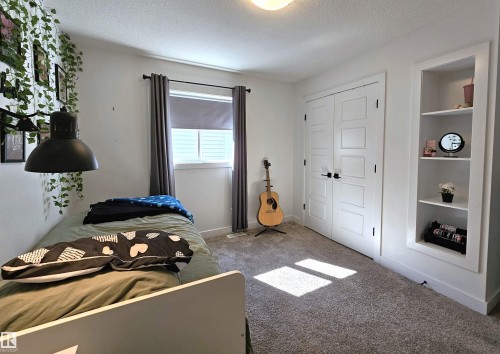 Built-in shelving, white paneled double doors, neutral carpet, single window with blinds, and recessed lighting - 40 Jamison Crescent, St. Albert, AB 