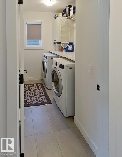 Laundry area featuring light tile flooring, a window with a roller shade, and built-in shelving - 40 Jamison Crescent, St. Albert, AB 