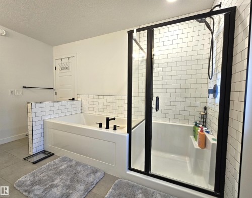 Subway tile walls, black-framed glass shower enclosure, integrated shower shelf, and matte black fixtures - 40 Jamison Crescent, St. Albert, AB 