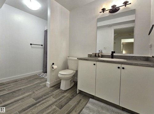 Vanity with white cabinetry, a flat-panel mirror, and a three-light fixture - 40 Jamison Crescent, St. Albert, AB 