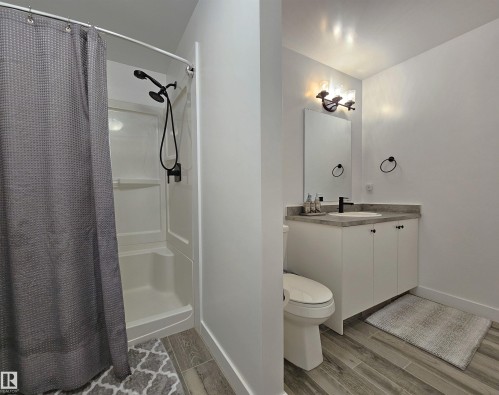 Contemporary bathroom featuring wood-finish tile flooring and a white vanity with a light-toned countertop - 40 Jamison Crescent, St. Albert, AB 