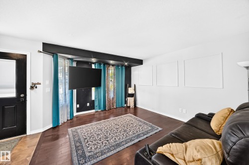Wood-finish flooring throughout, featuring a dark-toned entrance door with a window panel - 447 Songhurst Place, Leduc, AB 