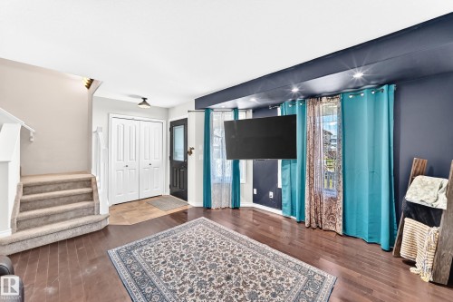 Hardwood-finish flooring, recessed ceiling lighting, a prominent staircase with carpeted treads, and a built-in closet with bifold doors - 447 Songhurst Place, Leduc, AB 