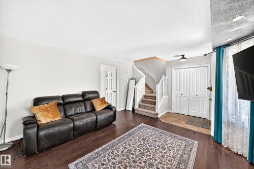 Wood-finish flooring, staircase with carpeted treads and white railings, recessed ceiling lighting, and a double-door closet - 447 Songhurst Place, Leduc, AB 
