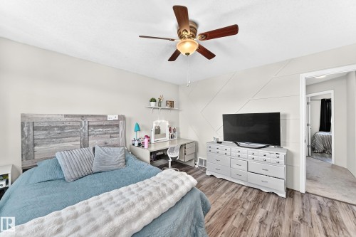 Wood-finish flooring, accent wall detailing, ceiling fan with light fixture, and an open doorway - 447 Songhurst Place, Leduc, AB 