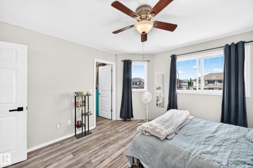 Wood-finish flooring, multiple windows, ceiling fan with integrated lighting, and a white paneled door with black hardware - 447 Songhurst Place, Leduc, AB 