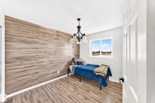 Wood-finish flooring, accent wall with horizontal wood-finish paneling, white painted walls, white trim, and a built-in light fixture - 447 Songhurst Place, Leduc, AB 
