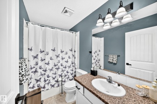 Bathroom featuring a single vanity with an integrated sink, polished chrome faucet, and a wall-mounted mirror - 447 Songhurst Place, Leduc, AB 