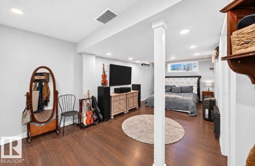 Spacious room featuring wood-finish flooring, recessed lighting, and a window providing natural light - 447 Songhurst Place, Leduc, AB 