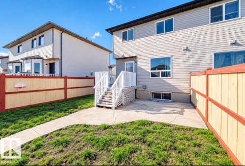 Private rear yard with concrete patio, white deck, and light-toned wood fencing - 447 Songhurst Place, Leduc, AB 