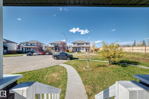 Front porch with white railings, a concrete walkway, and a landscaped lawn - 447 Songhurst Place, Leduc, AB 