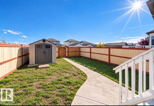 Expansive backyard featuring a privacy fence, concrete pathway, and a detached storage shed - 447 Songhurst Place, Leduc, AB 