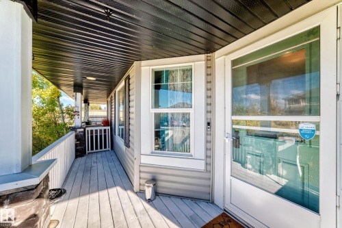 Covered front porch with composite decking and white railings - 447 Songhurst Place, Leduc, AB 