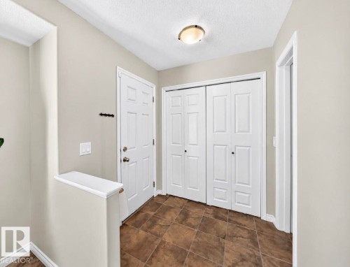 Entryway with tiled flooring, white bi-fold closet doors, a white paneled door, and a flush mount ceiling light - 447 Songhurst Place, Leduc, AB 