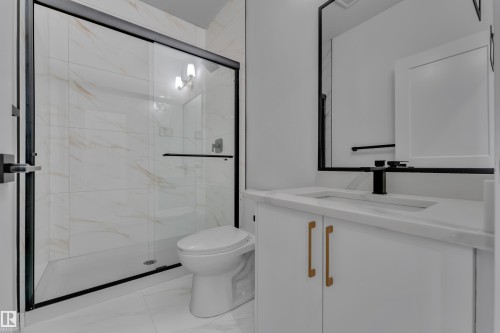 White vanity with gold-tone hardware, rectangular undermount sink, and black faucet - 178 Munn Way, Leduc, AB 