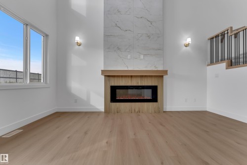 Wood-finish flooring throughout, featuring a fireplace with a wood mantel and a tile surround - 178 Munn Way, Leduc, AB 