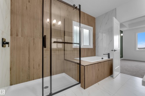 Shower with black-framed glass enclosure, built-in bathtub with wood-finish surround, wood-finish wall paneling, and white tile flooring - 178 Munn Way, Leduc, AB 