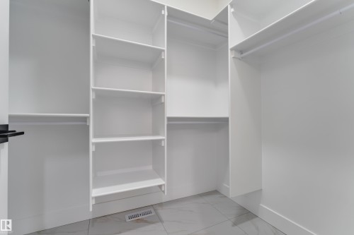 Integrated closet system featuring white shelving and hanging rods - 178 Munn Way, Leduc, AB 