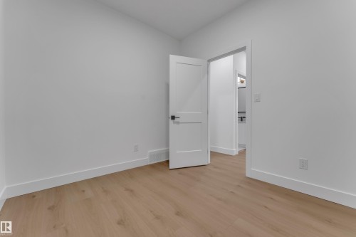 Light wood-finish flooring with white baseboards and a contrasting interior door with dark hardware - 178 Munn Way, Leduc, AB 