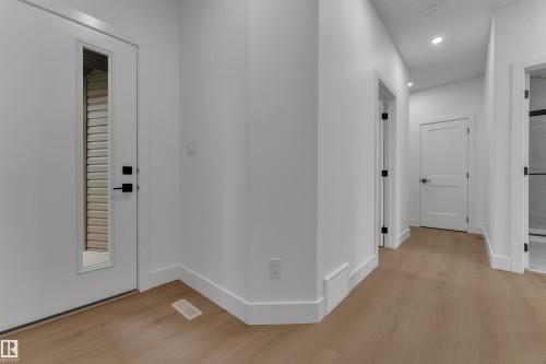 Light wood-finish flooring extends throughout, complemented by white walls and trim - 178 Munn Way, Leduc, AB 