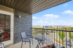 Balcony featuring a black wrought iron railing, stone veneer wall, and overhead soffit with recessed lighting - 