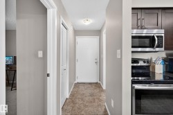 Hallway featuring tile flooring, a flush-mount ceiling light, and white trim - 