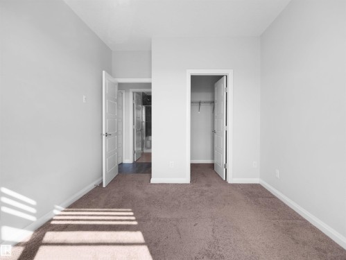 Neutral wall paint, brown carpet flooring, and a built-in closet with shelving and hanging rod - #415 2588 Anderson Wy Sw, Edmonton, AB 