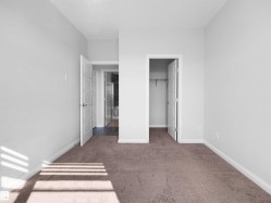 Neutral wall paint, brown carpet flooring, and a built-in closet with shelving and hanging rod - 