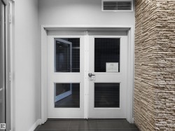 Double doors with glass inserts, stone accent wall, and dark tile flooring - 