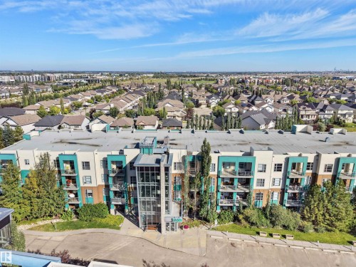 Multi-story building featuring modern exterior finishes, multiple balconies, and a prominent glass-enclosed entrance - #415 2588 Anderson Wy Sw, Edmonton, AB 