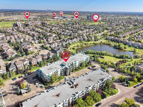 Aerial perspective of a multi-story residential building, an adjacent parking area, and a large body of water - #415 2588 Anderson Wy Sw, Edmonton, AB 