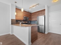 Kitchen featuring wood-finish cabinetry, stainless steel appliances, granite-look countertops, subway tile backsplash, and wood-finish flooring - 