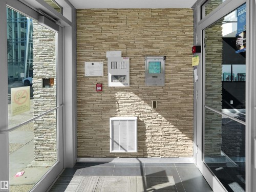 Textured stone accent wall with integrated security panel and fire alarm - #415 2588 Anderson Wy Sw, Edmonton, AB 