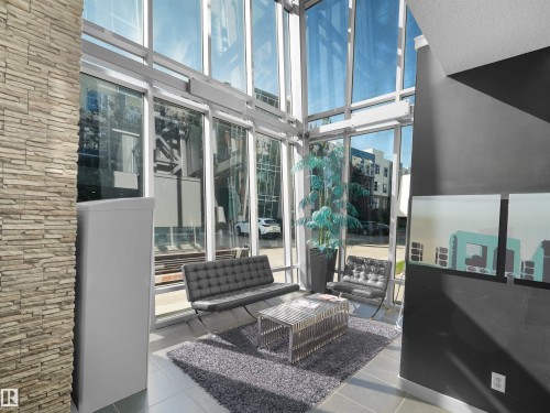 Floor-to-ceiling windows, stone veneer column, tile flooring, and dark-finished walls - #415 2588 Anderson Wy Sw, Edmonton, AB 
