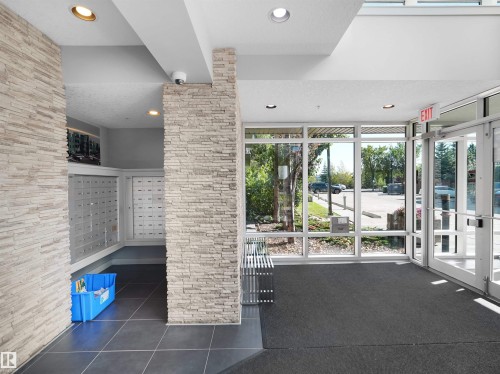 Entryway with large windows, stone-clad columns, mailboxes, and recessed lighting - #415 2588 Anderson Wy Sw, Edmonton, AB 