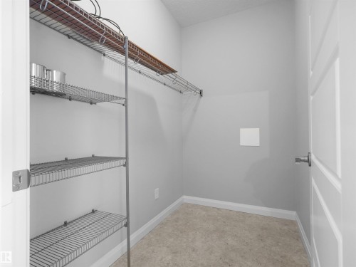 Wall-mounted wire shelving system with a wood-finish top shelf - #415 2588 Anderson Wy Sw, Edmonton, AB 